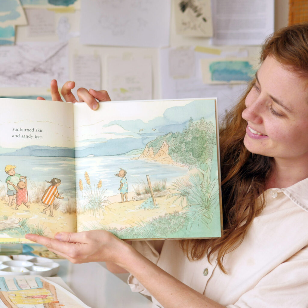 Hilary Tapper holding At the Bach open to a page showing children on a beach.
